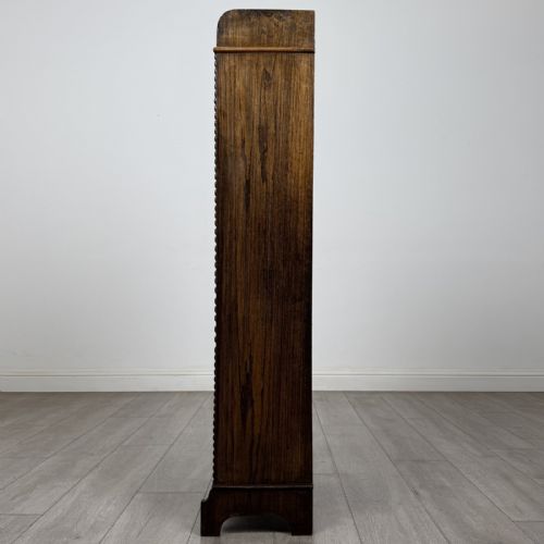 fig 3. A tall, narrow dark oak open bookcase featuring four fixed shelves, beaded front stiles, and a low arched top gallery rail.