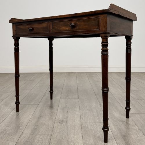 fig 1. An antique dark mahogany Regency writing table featuring two front drawers with turned wooden knobs and four tapered ring-turned legs.