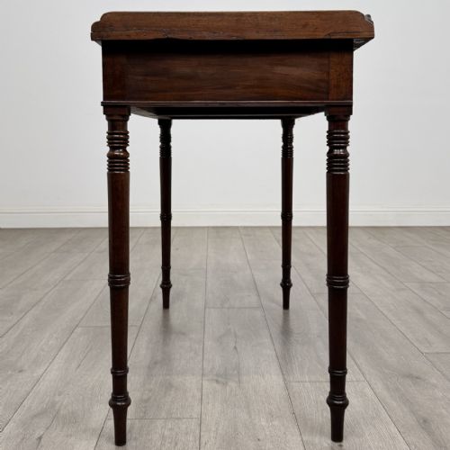 fig 2. An antique dark mahogany Regency writing table featuring two front drawers with turned wooden knobs and four tapered ring-turned legs.