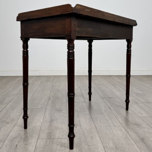fig 3. An antique dark mahogany Regency writing table featuring two front drawers with turned wooden knobs and four tapered ring-turned legs.