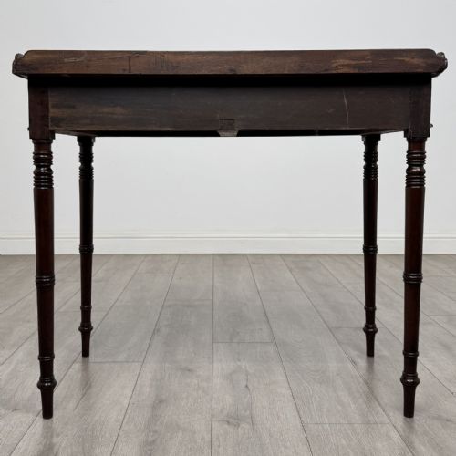 fig 4. An antique dark mahogany Regency writing table featuring two front drawers with turned wooden knobs and four tapered ring-turned legs.
