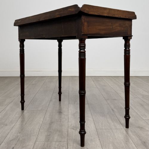 fig 5. An antique dark mahogany Regency writing table featuring two front drawers with turned wooden knobs and four tapered ring-turned legs.