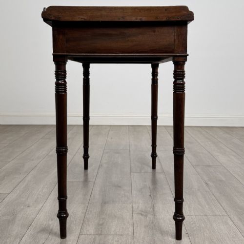 fig 6. An antique dark mahogany Regency writing table featuring two front drawers with turned wooden knobs and four tapered ring-turned legs.