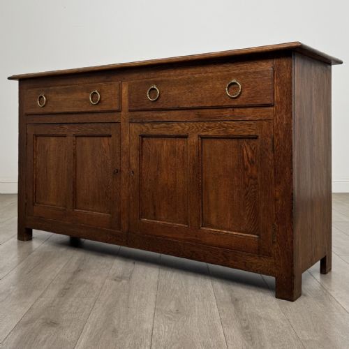 fig 1. A dark oak early 20th-century sideboard featuring two top drawers with circular brass ring pulls over two panelled cupboard doors.