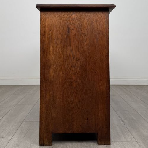 fig 6. A dark oak early 20th-century sideboard featuring two top drawers with circular brass ring pulls over two panelled cupboard doors.