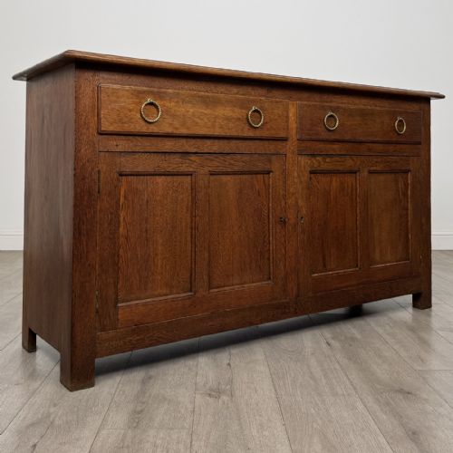 fig 7. A dark oak early 20th-century sideboard featuring two top drawers with circular brass ring pulls over two panelled cupboard doors.