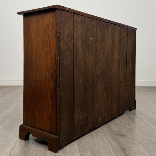 fig 3. A Georgian style warm brown oak dresser base featuring two drawers with brass drop handles above two panelled cupboard doors, raised on bracket feet.