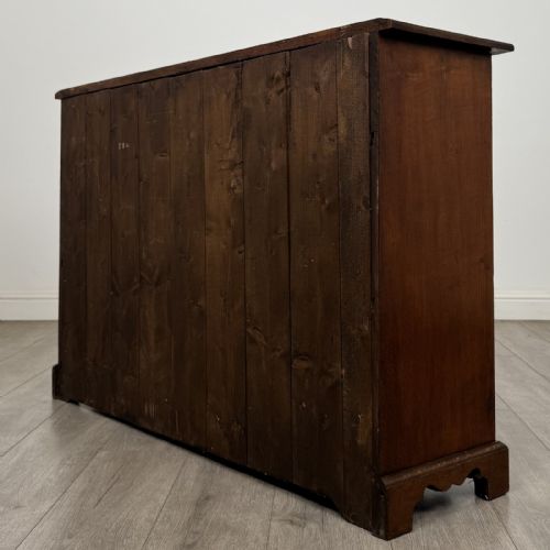 fig 5. A Georgian style warm brown oak dresser base featuring two drawers with brass drop handles above two panelled cupboard doors, raised on bracket feet.