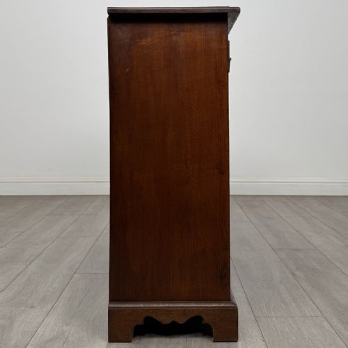 fig 6. A Georgian style warm brown oak dresser base featuring two drawers with brass drop handles above two panelled cupboard doors, raised on bracket feet.
