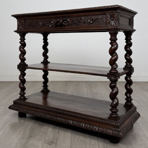 fig 1. A dark oak three-tier buffet featuring relief foliage carving across the top drawer frieze and four barley twist corner support legs.