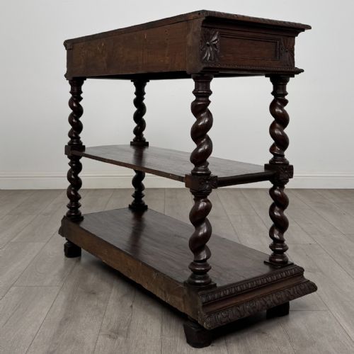 fig 5. A dark oak three-tier buffet featuring relief foliage carving across the top drawer frieze and four barley twist corner support legs.