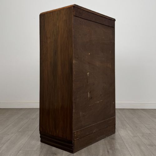 fig 3. An Art Deco walnut tallboy cabinet featuring highly figured book-matched veneer, double doors over two long drawers, vertical metal handles, and a stepped plinth base.