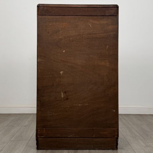 fig 4. An Art Deco walnut tallboy cabinet featuring highly figured book-matched veneer, double doors over two long drawers, vertical metal handles, and a stepped plinth base.