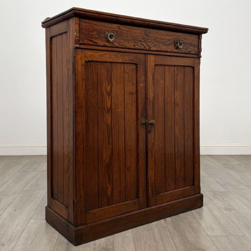 fig 7. A Victorian pitch pine cupboard featuring a single top drawer with brass drop ring handles above a two-door cabinet with vertical panelled detailing.