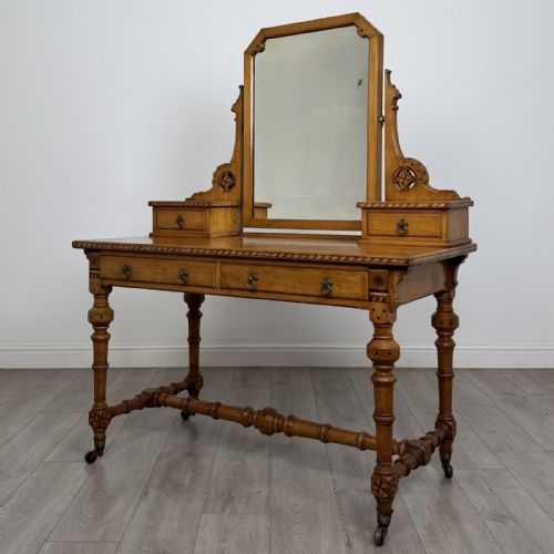 fig 1. An antique Victorian Gothic oak dressing table featuring a central adjustable swing mirror, pierced tracery supports, two upper trinket drawers, two main drawers, inlaid borders, turned legs, and brass ring handles.