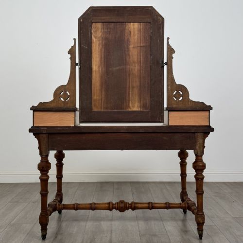 fig 4. An antique Victorian Gothic oak dressing table featuring a central adjustable swing mirror, pierced tracery supports, two upper trinket drawers, two main drawers, inlaid borders, turned legs, and brass ring handles.