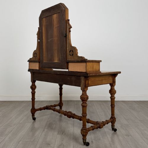 fig 5. An antique Victorian Gothic oak dressing table featuring a central adjustable swing mirror, pierced tracery supports, two upper trinket drawers, two main drawers, inlaid borders, turned legs, and brass ring handles.
