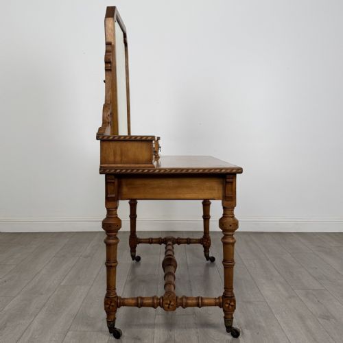 fig 6. An antique Victorian Gothic oak dressing table featuring a central adjustable swing mirror, pierced tracery supports, two upper trinket drawers, two main drawers, inlaid borders, turned legs, and brass ring handles.