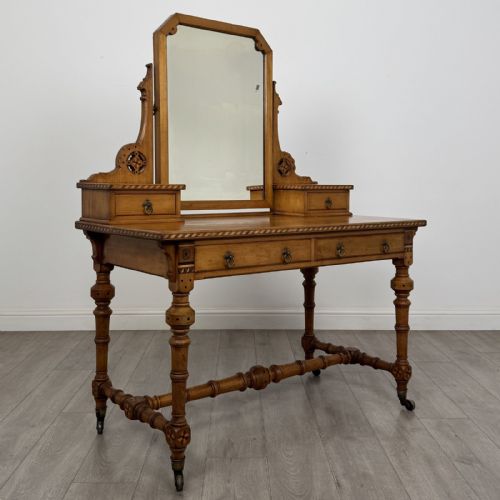 fig 7. An antique Victorian Gothic oak dressing table featuring a central adjustable swing mirror, pierced tracery supports, two upper trinket drawers, two main drawers, inlaid borders, turned legs, and brass ring handles.