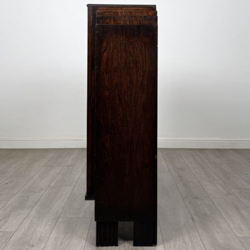 fig 2. A dark oak Art Deco display cabinet with two glazed doors, geometric glazing bars, stepped side shoulders, and reeded square feet.