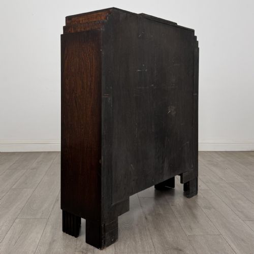 fig 3. A dark oak Art Deco display cabinet with two glazed doors, geometric glazing bars, stepped side shoulders, and reeded square feet.