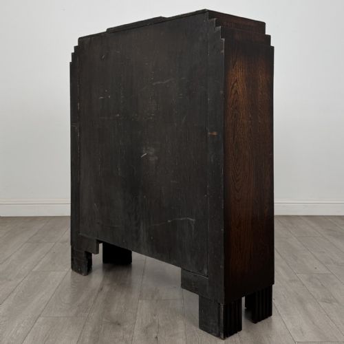 fig 5. A dark oak Art Deco display cabinet with two glazed doors, geometric glazing bars, stepped side shoulders, and reeded square feet.