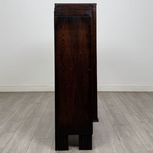 fig 6. A dark oak Art Deco display cabinet with two glazed doors, geometric glazing bars, stepped side shoulders, and reeded square feet.