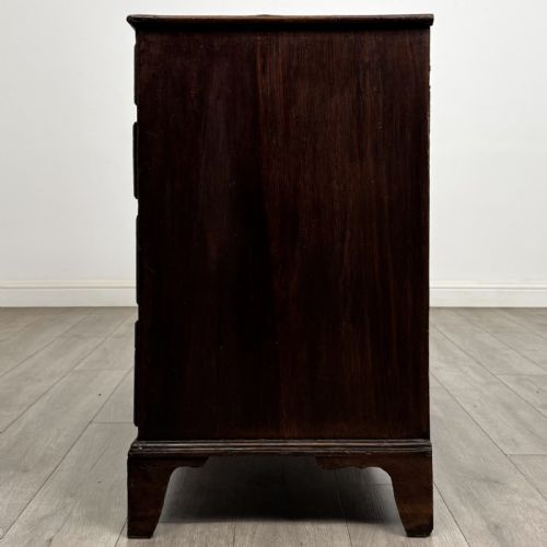 fig 2. An 18th-century dark oak Georgian chest of drawers featuring a two-short-over-three-long drawer configuration, brass handles, and bracket feet.
