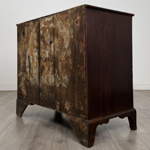 fig 5. An 18th-century dark oak Georgian chest of drawers featuring a two-short-over-three-long drawer configuration, brass handles, and bracket feet.