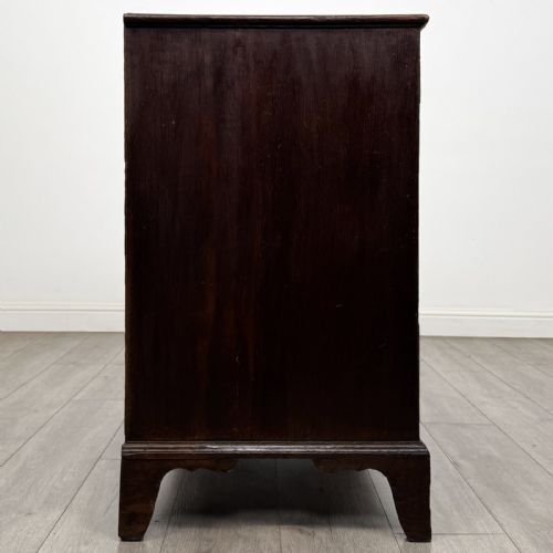fig 6. An 18th-century dark oak Georgian chest of drawers featuring a two-short-over-three-long drawer configuration, brass handles, and bracket feet.