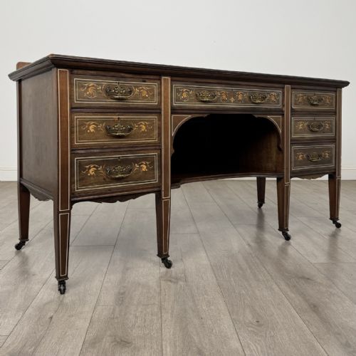fig 7. An Edwardian mahogany sideboard featuring detailed foliate marquetry inlay, seven drawers with brass handles, an arched central apron, and tapered legs with castors.