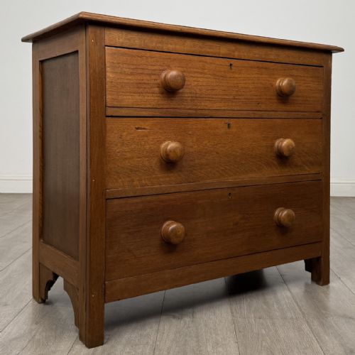 fig 7. A small 20th-century warm brown oak chest of drawers featuring three wide drawers with turned wooden knobs.