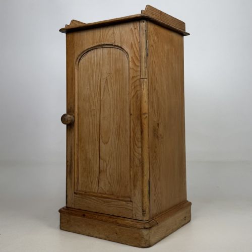 fig 1. An antique natural pine pot cupboard featuring a single arched panel door, turned wooden knob handle, side top galleries, and a solid plinth base.
