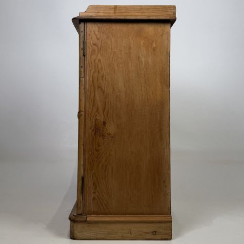 fig 2. An antique natural pine pot cupboard featuring a single arched panel door, turned wooden knob handle, side top galleries, and a solid plinth base.