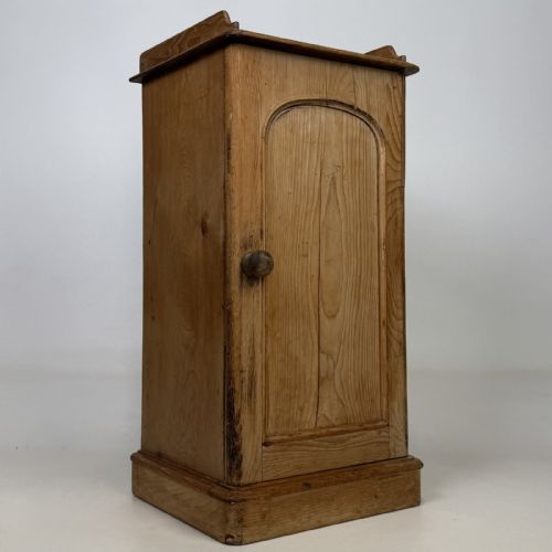 fig 7. An antique natural pine pot cupboard featuring a single arched panel door, turned wooden knob handle, side top galleries, and a solid plinth base.