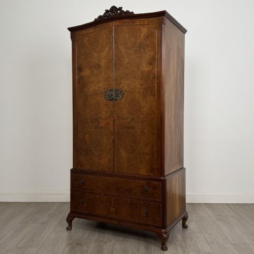 fig 1. A Queen Anne style burr walnut double-door wardrobe featuring two lower drawers, central metal hardware, and carved cabriole legs.