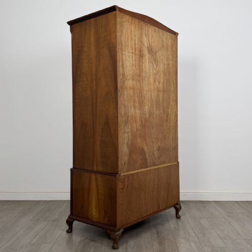 fig 3. A Queen Anne style burr walnut double-door wardrobe featuring two lower drawers, central metal hardware, and carved cabriole legs.