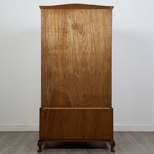 fig 4. A Queen Anne style burr walnut double-door wardrobe featuring two lower drawers, central metal hardware, and carved cabriole legs.