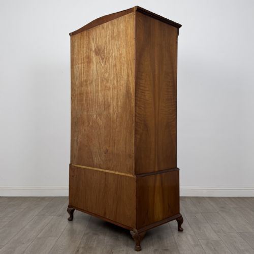 fig 5. A Queen Anne style burr walnut double-door wardrobe featuring two lower drawers, central metal hardware, and carved cabriole legs.