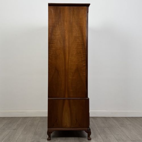 fig 6. A Queen Anne style burr walnut double-door wardrobe featuring two lower drawers, central metal hardware, and carved cabriole legs.