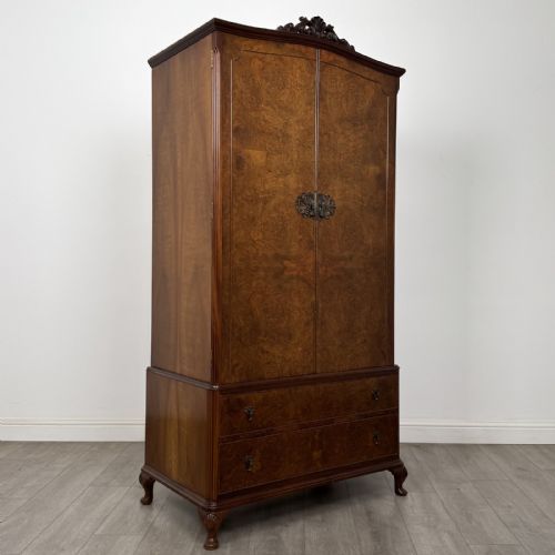 fig 7. A Queen Anne style burr walnut double-door wardrobe featuring two lower drawers, central metal hardware, and carved cabriole legs.