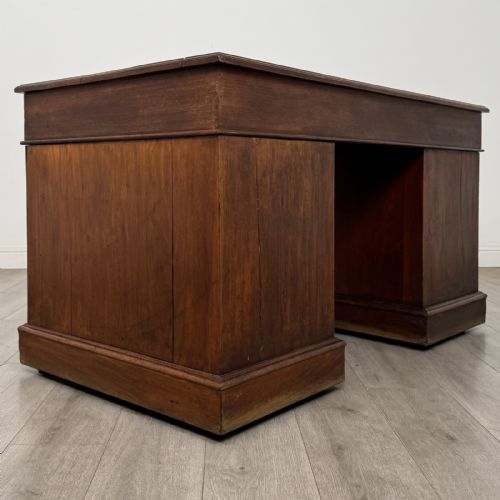 fig 3. A 19th-century walnut pedestal desk featuring nine drawers with brass handles and a plinth base.