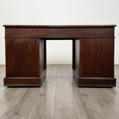 fig 4. A 19th-century walnut pedestal desk featuring nine drawers with brass handles and a plinth base.
