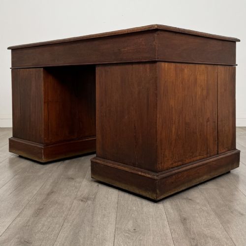 fig 5. A 19th-century walnut pedestal desk featuring nine drawers with brass handles and a plinth base.
