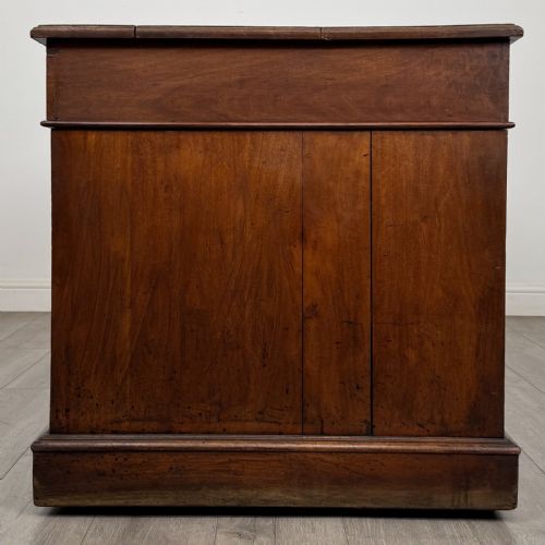 fig 6. A 19th-century walnut pedestal desk featuring nine drawers with brass handles and a plinth base.