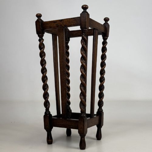 fig 1. An early 20th-century dark oak umbrella stand featuring four barley twist columns topped with small finials.