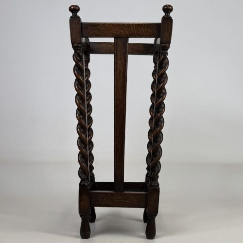 fig 2. An early 20th-century dark oak umbrella stand featuring four barley twist columns topped with small finials.
