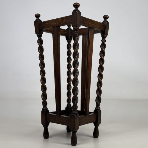 fig 3. An early 20th-century dark oak umbrella stand featuring four barley twist columns topped with small finials.