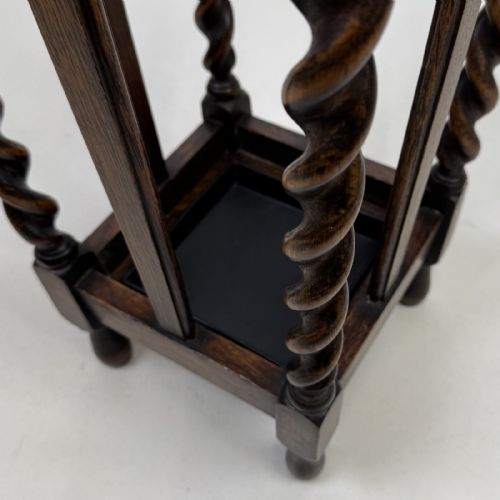 fig 7. An early 20th-century dark oak umbrella stand featuring four barley twist columns topped with small finials.