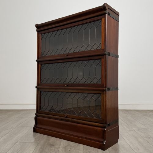 fig 1. A three-tier dark mahogany Globe Wernicke sectional bookcase featuring geometric leaded glass doors.